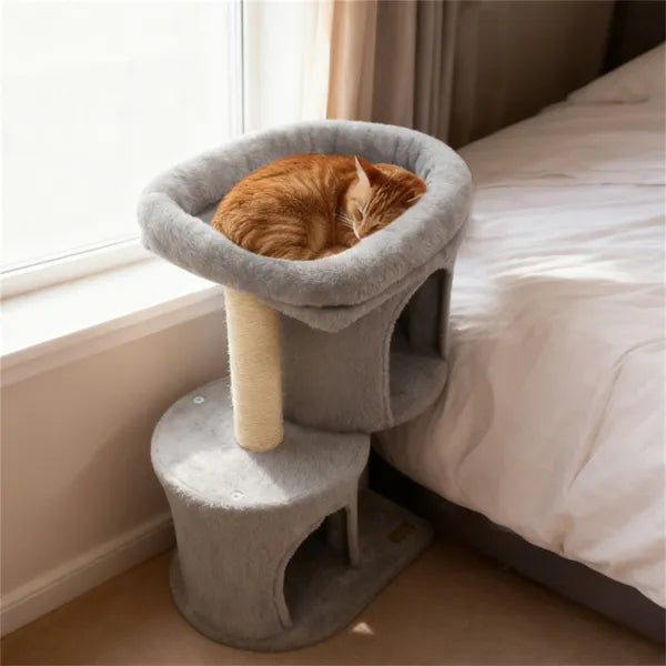Cat resting on a gray cat tree next to a bed in a room with a window.