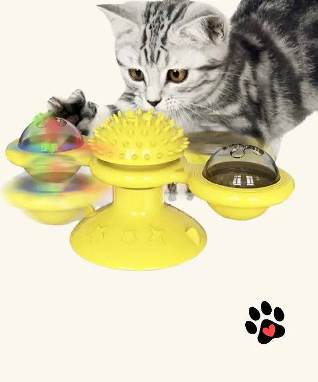 Cat playing with a yellow interactive pet toy on a white background